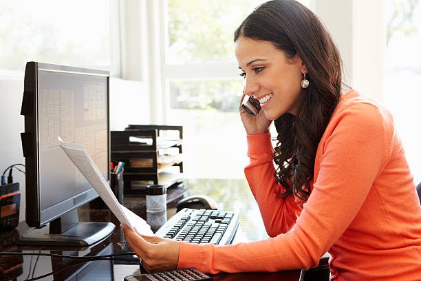 Hispanic woman working in home office on the phone smiling.